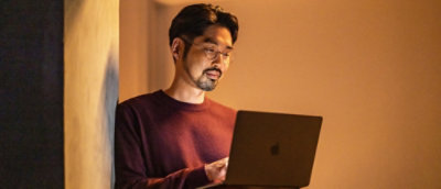 A man in a maroon shirt using a laptop.