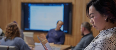 A group of people indoor. A woman holding a laptop.