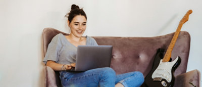 A woman sitting on a couch using a laptop.