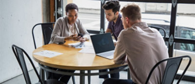A group of people sitting around a table with laptops.