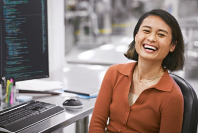 Person seated at a workstation with code on a monitor.