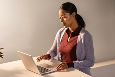 Person using a laptop at a desk in a bright workspace.