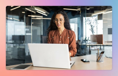 A woman wearing glasses working on a laptop.