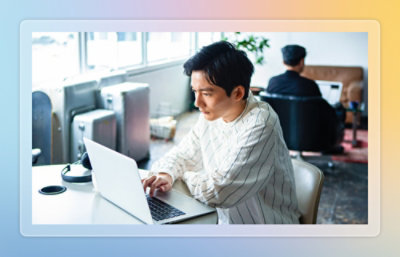 Person working on a laptop at a desk in a shared office environment.