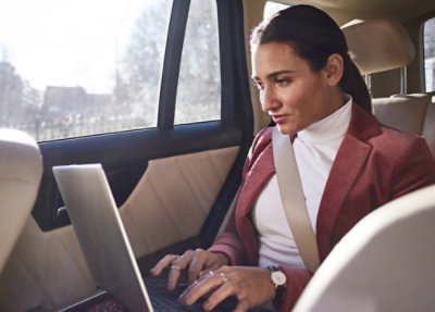 A person sitting in a car using a laptop.