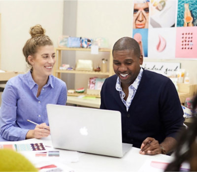 A man and woman looking at a laptop.