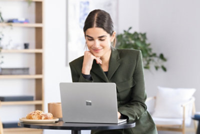A person in a green jacket using a laptop at a table.