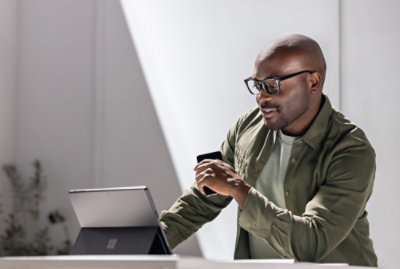 A man wearing glasses looking at a laptop.