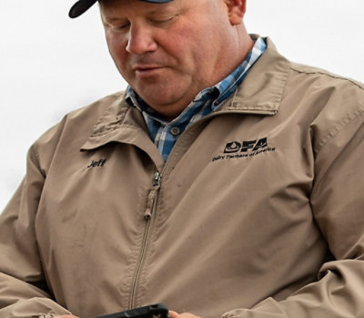 A man wearing a hat and jacket looks at a cellphone, with the text DFA visible.