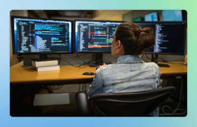 A person sitting at a desk with multiple computer screens.