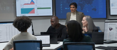 A woman sitting at a desk looking at a laptop.