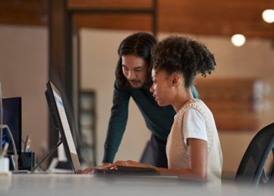 Two people working together at a desktop computer