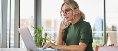 A woman in a green shirt typing on a laptop.