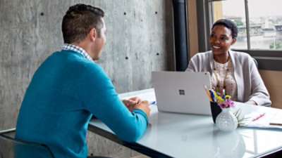 A man and woman sitting at a table with a laptop.