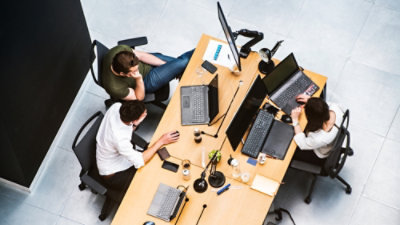 A group of people sitting at a table with laptops.