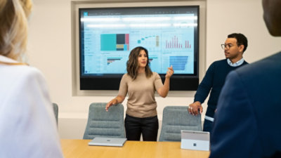 A man and woman standing in front of a large screen.