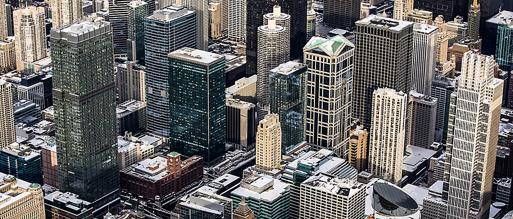 Aerial view of a dense urban cityscape with numerous high-rise buildings in various architectural styles.