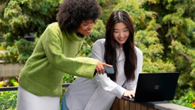 Two girls are discussing by looking at laptop