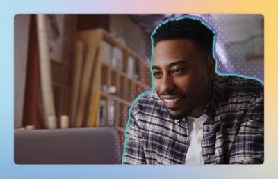 A man smiling while sitting at a desk with a laptop.