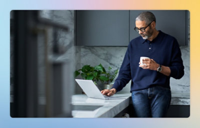 A man holding a cup and using a laptop.