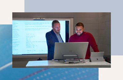 Grupa muškaraca stoji ispred računara.