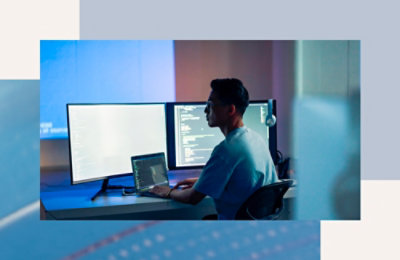 Osoba sedi za stolom sa laptopom, u pozadini je bela tabla.