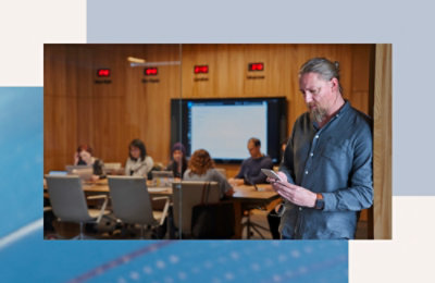 Muškarac drži telefon ispred grupe ljudi.