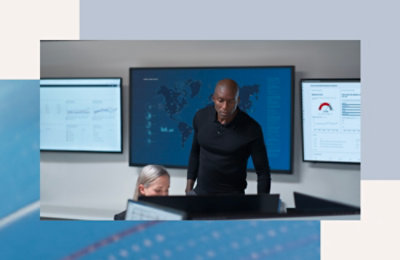 Ljudi rade u kontrolnoj sobi sa velikim prikazima podataka na monitorima.