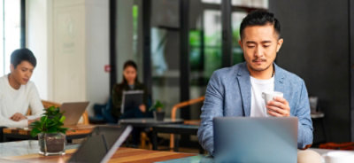 Osoba sedi za stolom sa laptopom.