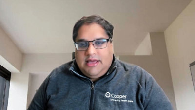 Healthcare professional wearing a Cooper University Health Care jacket indoors.