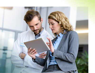 Two professionals discussing information on a tablet in a modern workspace.