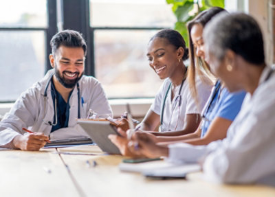 Colleagues seated around a table reviewing information on a tablet in a bright workspace