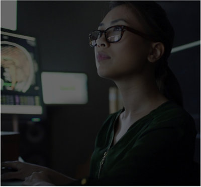 Person working at computer in dim workspace reviewing medical imaging on screen