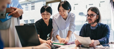 A group of people gathered around a laptop on a table.