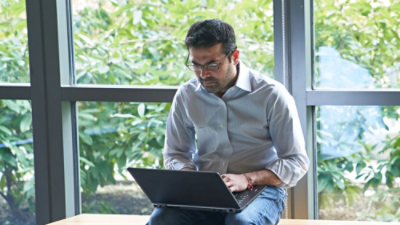 A man sitting on a bench using a laptop.