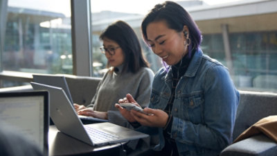 Two women sitting besides each other and working on their laptops