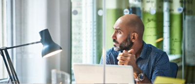 A man sitting in office environment and looking outside window