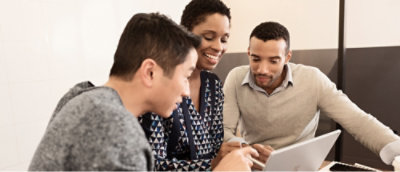 mall group gathered around a laptop, discussing and reviewing work together.