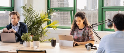 Team working at a shared table with laptops in a bright office environment.