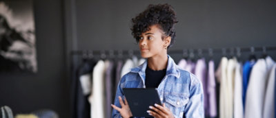 A woman with curly hair holding a tab.