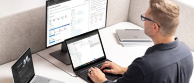 桌子上有一台笔记本电脑和一个台式机，前面坐着一个人。