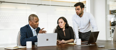 Um grupo de pessoas sentadas em volta de uma mesa com um laptop visível.