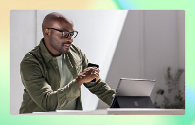 A man holding a tea cup and looking into laptop screen.