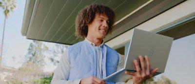 A man holding a laptop and smiling.