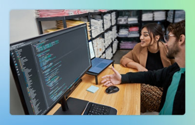 A man and woman sitting at a desk with a computer screen visible.