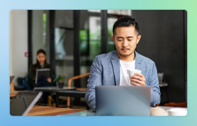 A man holding a cup and looking at a laptop.