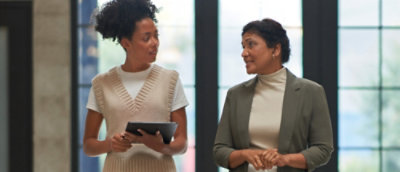 A woman holding a tablet and talking to a person.