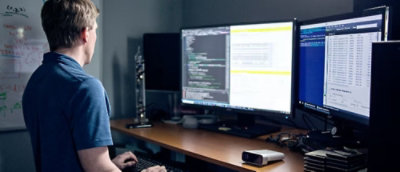 A man looking into a two big desktop screen.