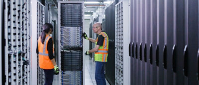 A man showing a electric board to a woman in a factory.
