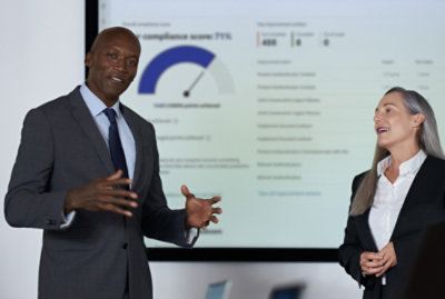 A man and woman standing in front of a presentation screen.